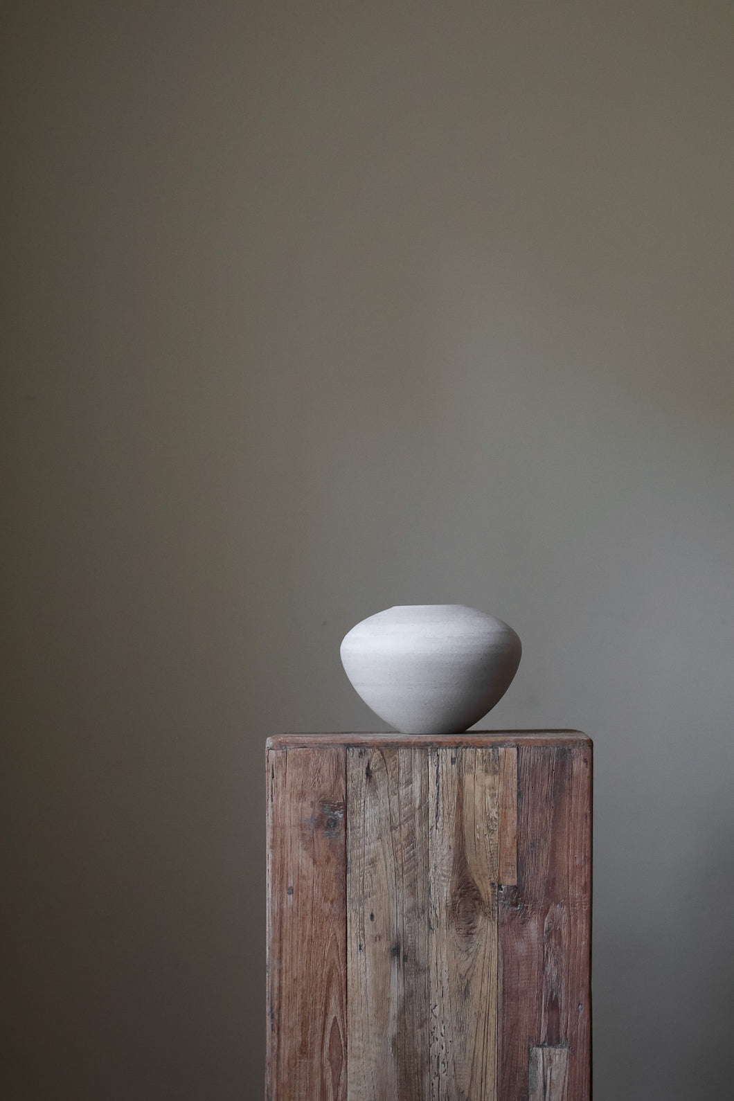 Small, contemporary ceramic bowl in a light neutral tone, featuring a subtly textured surface and a simple, rounded form.