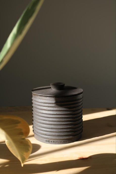 Elegant handmade lidded vessel in black with raw texture and glazed interior, perfect for upscale interiors as a ring holder, coin keeper, or incense container.